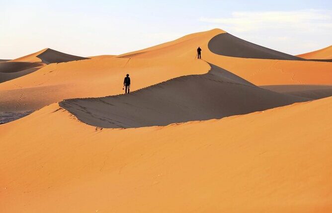 People walking sand dunes in the Moroccan Sahara Desert on a tour